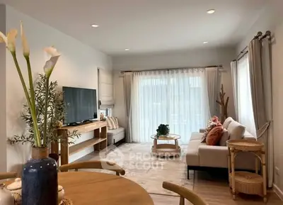 Stylish living room with modern decor, large TV, and natural light from big windows.