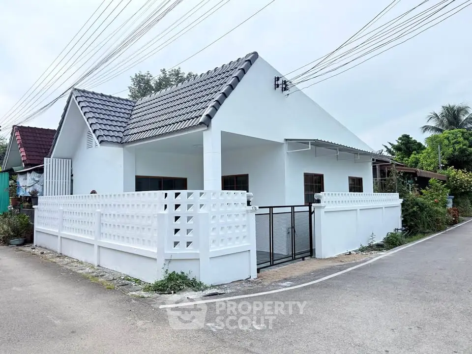 Charming white single-story house with modern fence and tiled roof in a peaceful neighborhood.