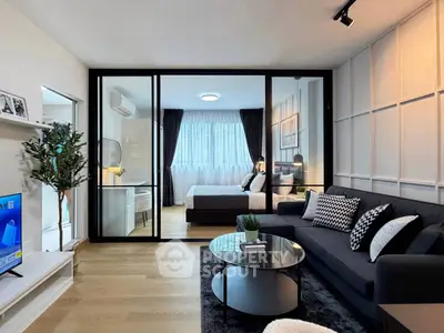 Modern living room with glass partition leading to stylish bedroom