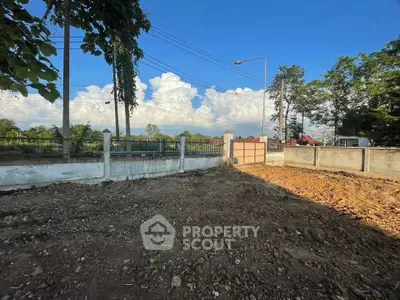 Vacant land plot with clear blue sky and lush greenery, ideal for development.