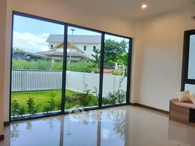 Spacious living room with large windows offering a serene garden view in a modern home.