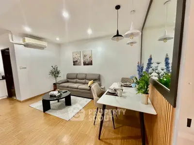 Modern living room with stylish decor and dining area, featuring cozy sofa and elegant lighting.