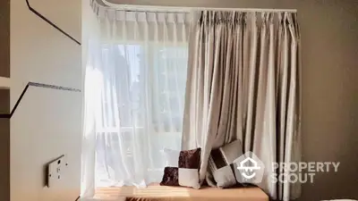 Cozy window nook with elegant curtains and decorative pillows in a modern home.