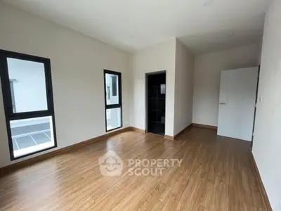 Spacious bedroom with wooden flooring and ample natural light.