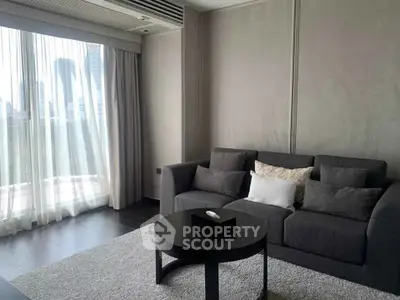 Modern living room with city view, featuring sleek gray sofa and stylish decor.