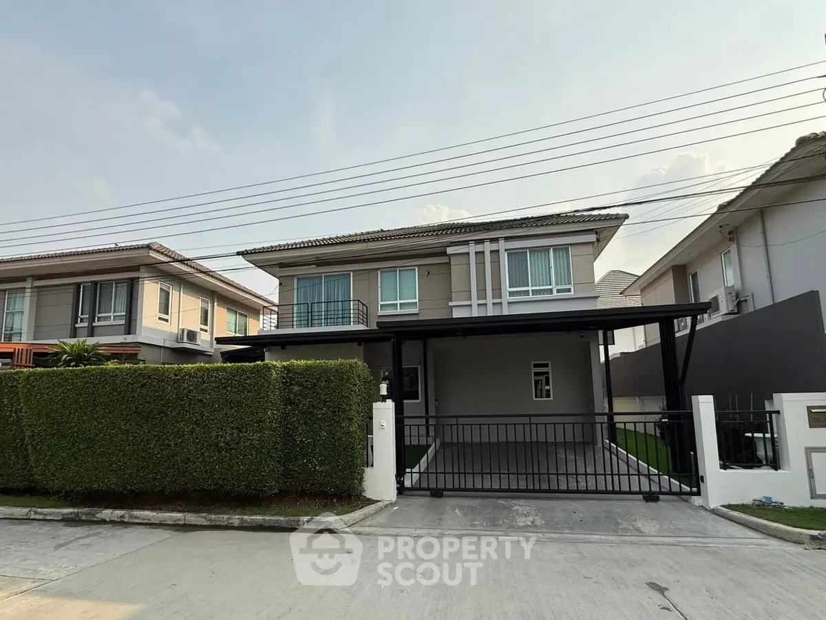 Modern two-story house with driveway and manicured hedge in suburban neighborhood.