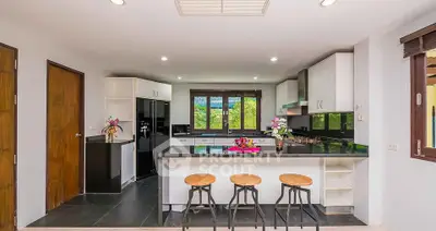 Modern kitchen with sleek black countertops and bar stools, offering a stylish and functional space.