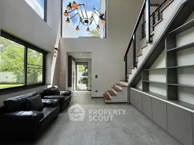 Modern living room with high ceiling, large windows, and stylish staircase in a contemporary home.