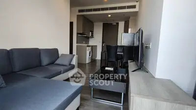 Modern living room with sleek furniture and open kitchen layout in a stylish apartment.