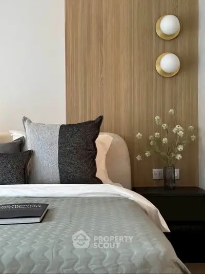 Elegant bedroom with modern decor and cozy bedding, featuring stylish wall lights and a sleek nightstand.