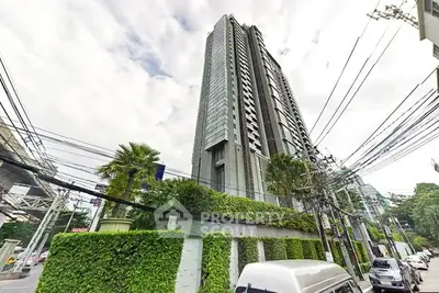 Modern high-rise condominium with lush greenery and urban surroundings.