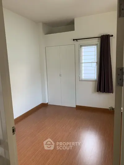 Spacious bedroom with wooden flooring and ample natural light