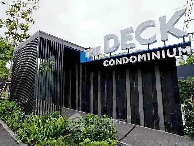Modern condominium entrance with sleek design and lush greenery.