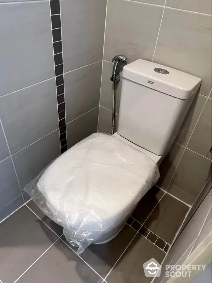 Modern bathroom with sleek tiled design and new toilet installation.