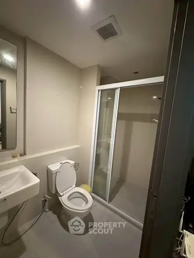Modern bathroom with shower enclosure and sleek fixtures in a contemporary apartment.