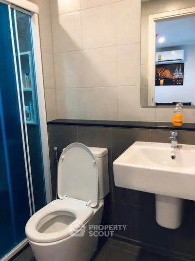 Modern bathroom with sleek design and glass shower enclosure in a contemporary apartment.
