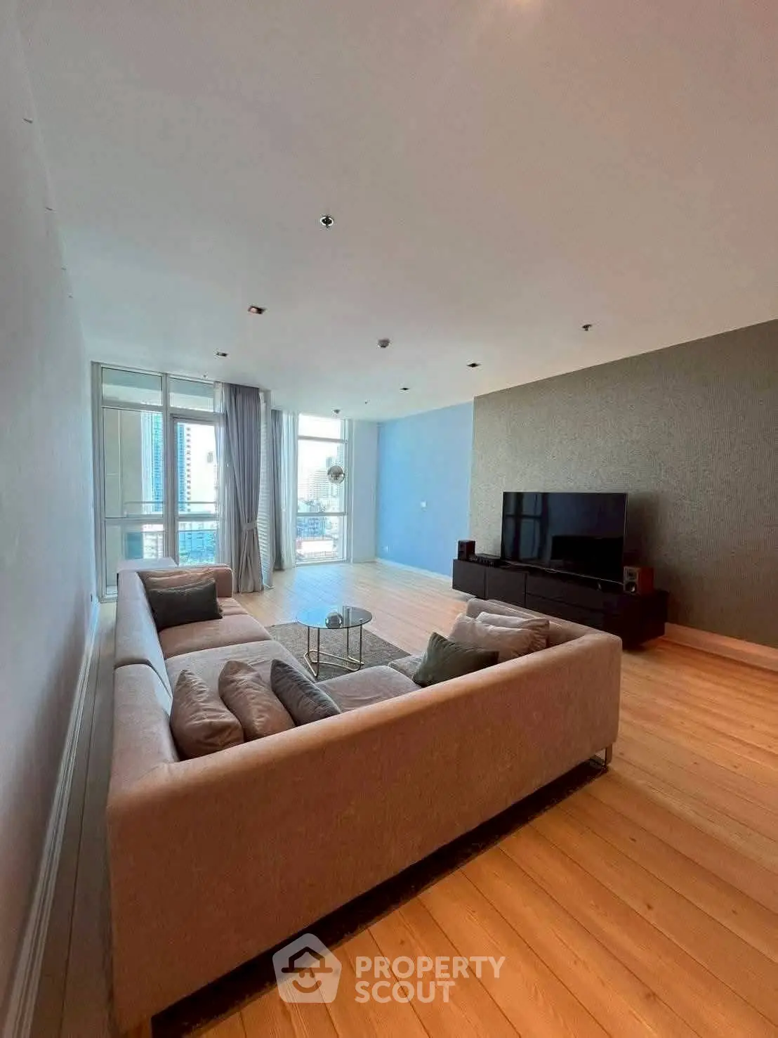 Spacious modern living room with large windows and elegant decor in a high-rise apartment.