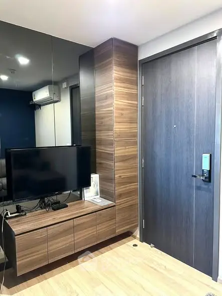 Modern apartment entrance with sleek wooden cabinetry and mounted TV