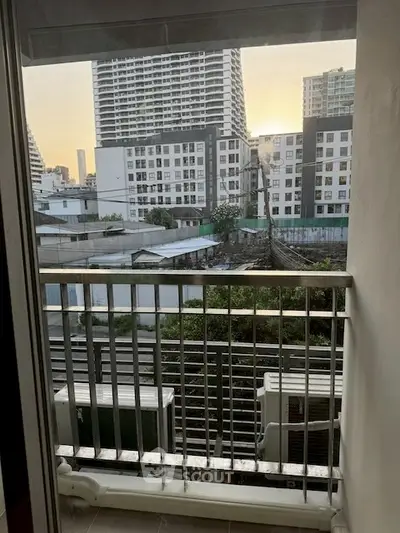 Urban apartment balcony with city view, showcasing modern high-rise buildings at sunset.