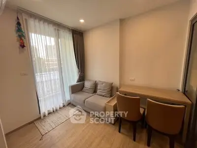 Cozy living room with modern sofa and dining table, featuring large window for natural light.