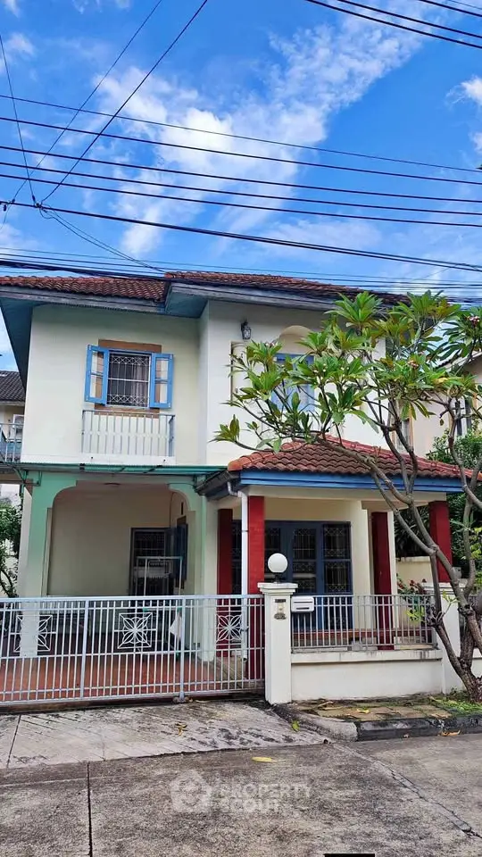 Charming two-story house with vibrant facade and lush garden in a serene neighborhood.