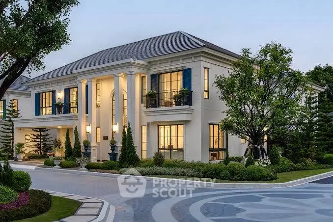 Luxurious mansion with grand columns and lush landscaping at dusk.