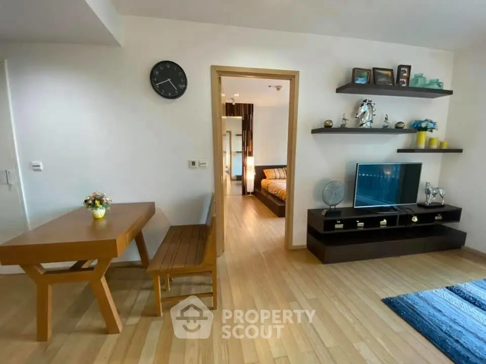 Modern living room with wooden flooring, stylish shelves, and a cozy dining area.