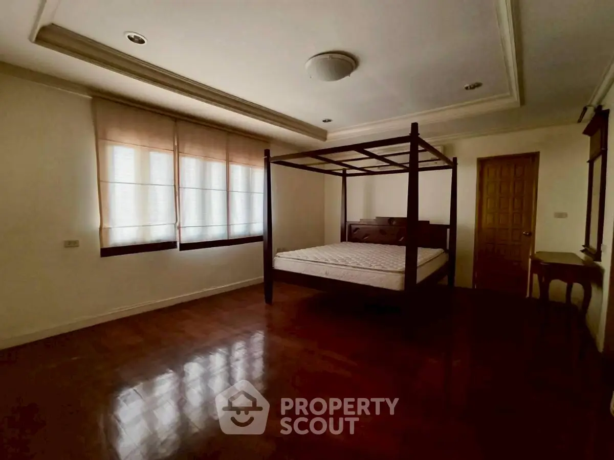 Spacious bedroom with elegant wooden flooring and canopy bed.