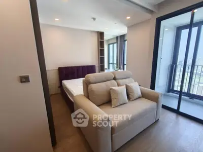 Modern bedroom with balcony and city view, featuring cozy sofa and stylish decor.