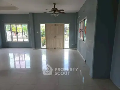 Spacious living room with large windows and ceiling fan, perfect for natural light.