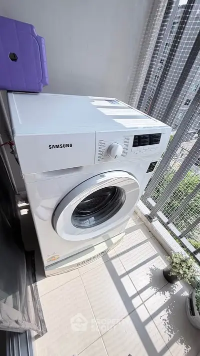Modern washing machine on a sunny balcony with city view, perfect for urban living convenience.
