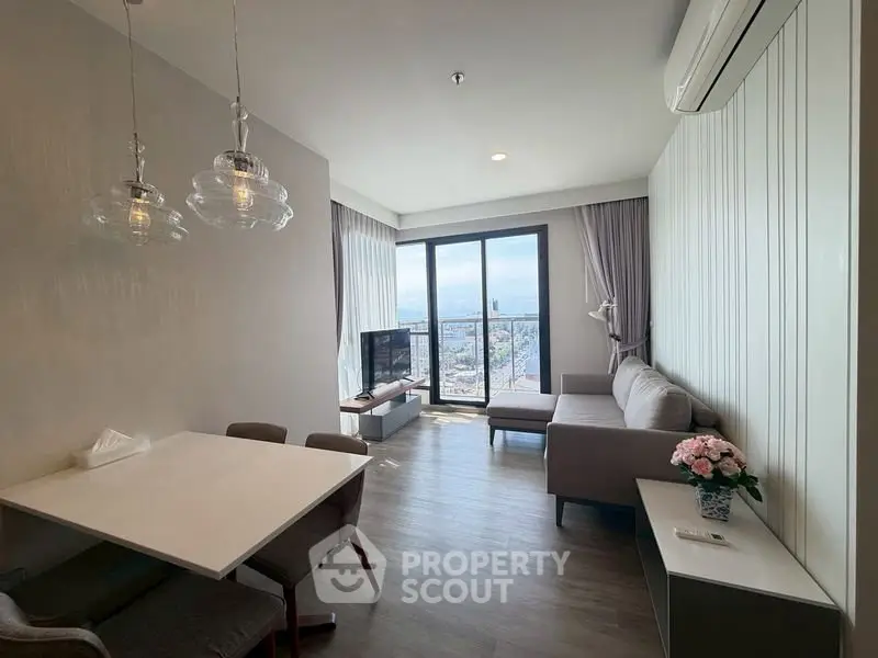 Modern living room with large windows and city view, featuring stylish furniture and elegant lighting.