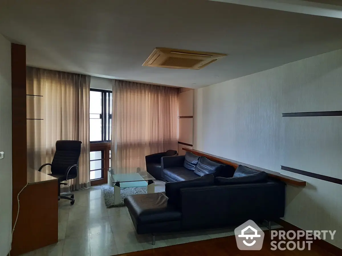 Spacious living room with polished wooden floors, large windows draped in soft curtains, and comfortable modern furniture, ideal for relaxation and entertaining.