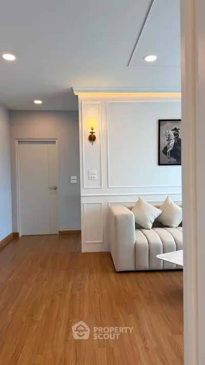 Elegant living room with modern decor and cozy sofa, featuring stylish wall paneling and warm wooden flooring.