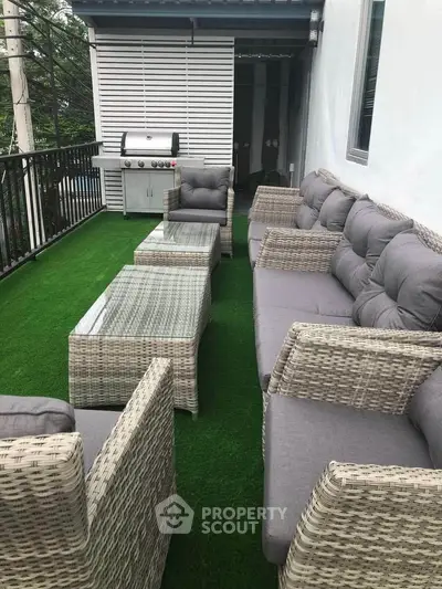 Charming balcony with cozy outdoor seating and BBQ grill, perfect for entertaining.