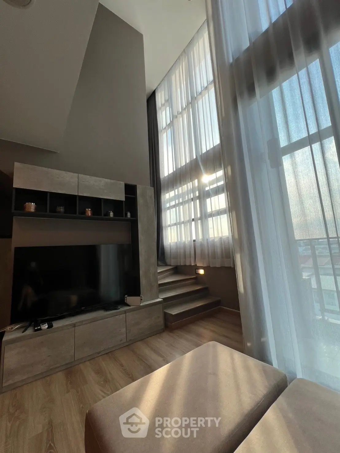 Modern living room with high ceilings and large windows offering stunning views.