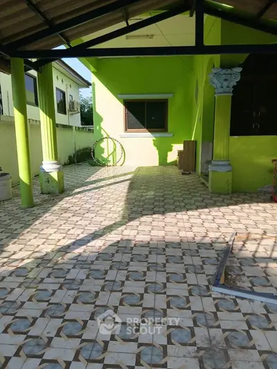 Spacious outdoor patio with tiled flooring and vibrant green walls, perfect for relaxation and gatherings.