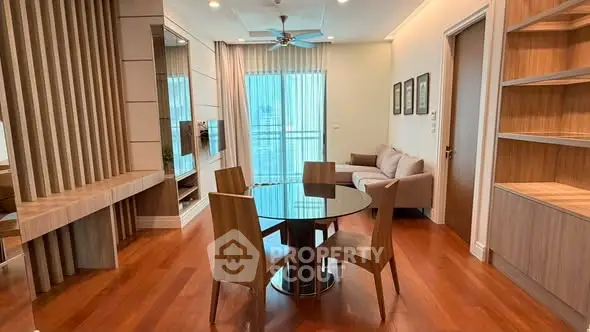 Modern living room with wooden flooring, stylish furniture, and large window offering natural light.