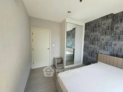 Modern bedroom with minimalist design and stylish wallpaper accent wall.