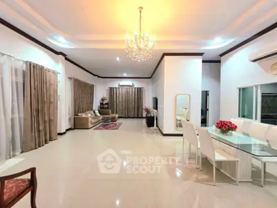 Spacious open-plan living and dining area with elegant chandelier and modern furnishings.