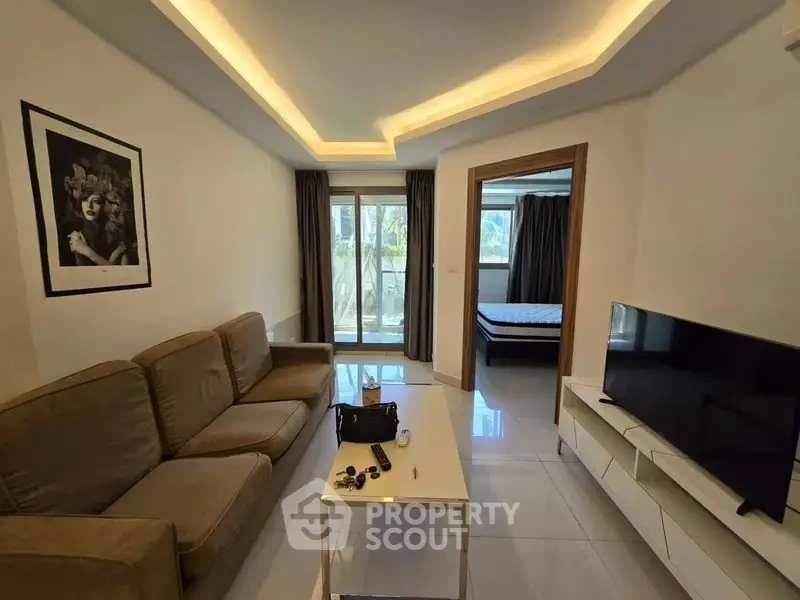 Modern living room with cozy sofa and TV, leading to a bright bedroom with balcony view.