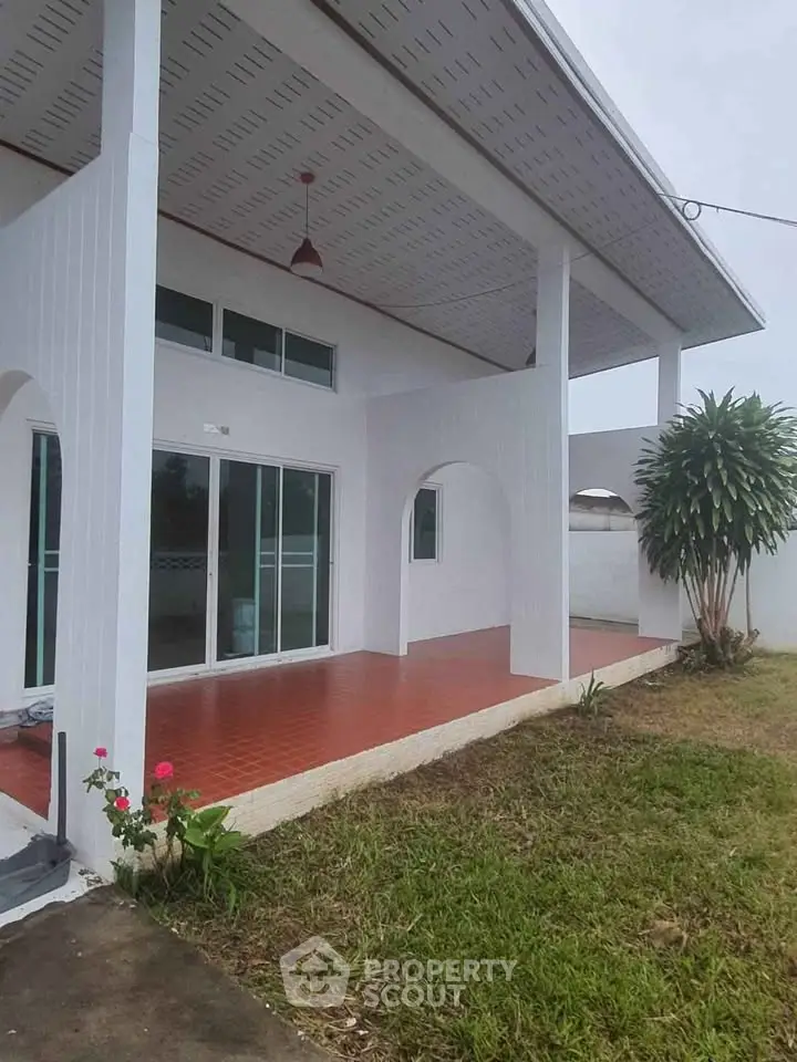 Charming white exterior with spacious patio and lush greenery, perfect for outdoor relaxation.