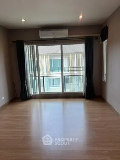 Spacious empty room with large windows and balcony access in modern apartment.