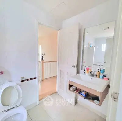 Bright bathroom with modern fixtures and open door to hallway