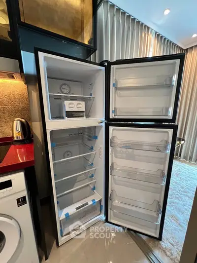 Modern kitchen with open fridge and washing machine in stylish apartment.