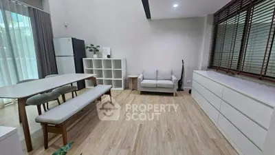 Modern living room with dining area, featuring sleek furniture and natural light.