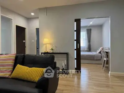 Modern living room with cozy seating and view into a stylish bedroom, perfect for comfortable living.