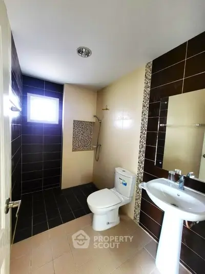 Modern bathroom with sleek design, featuring a shower, toilet, and pedestal sink.