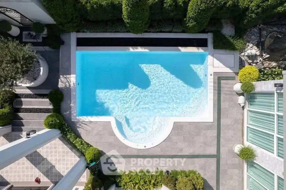 Luxurious aerial view of a modern villa with a pristine swimming pool and lush greenery.