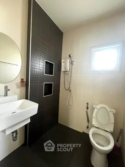 Modern bathroom with sleek design, featuring a shower, toilet, and stylish sink.